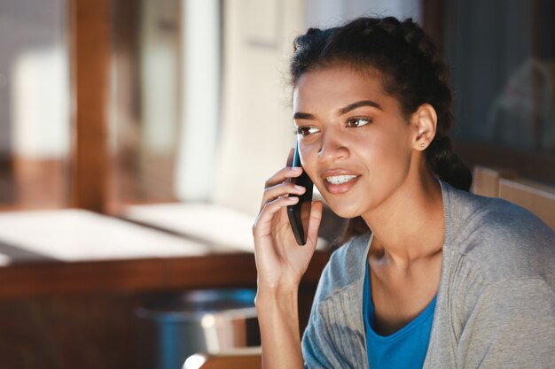 Hermosa chica alegre de piel oscura hablando por teléfono