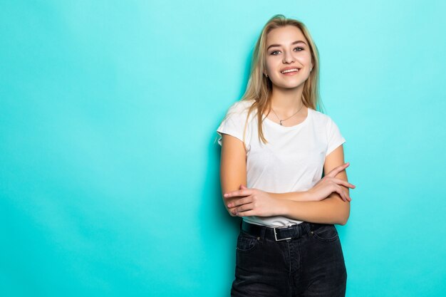 Hermosa chica alegre en top blanco sobre pared azul