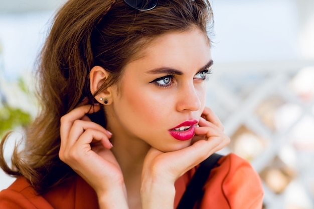 Hermosa chica de amistad joven elegante sentado en el restaurante de verano y soñando. Feliz soleado verano vacaciones humor, colores brillantes. Tiene labios rojos llenos y grandes ojos azules.