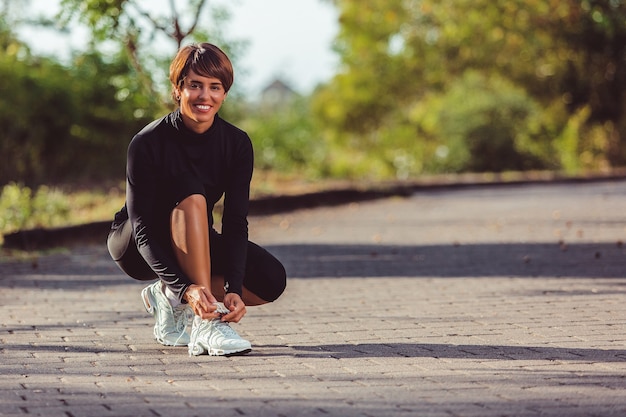 Hermosa chica ata los cordones de los zapatos.