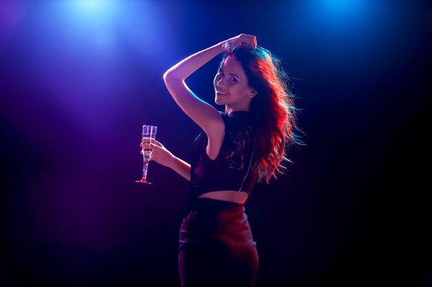 La hermosa chica bailando en la fiesta bebiendo champaña