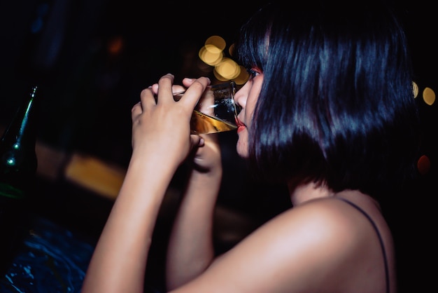 Hermosa chica bebiendo cerveza en un bar.