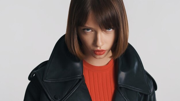 Hermosa chica con cabello bob y labios rojos posando en cámara con mirada de diablo aislada en fondo blanco