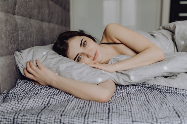 Foto gratuita hermosa chica en la cama hermosas mujeres jóvenes tumbado en el sofá y sonriendo a la cámara