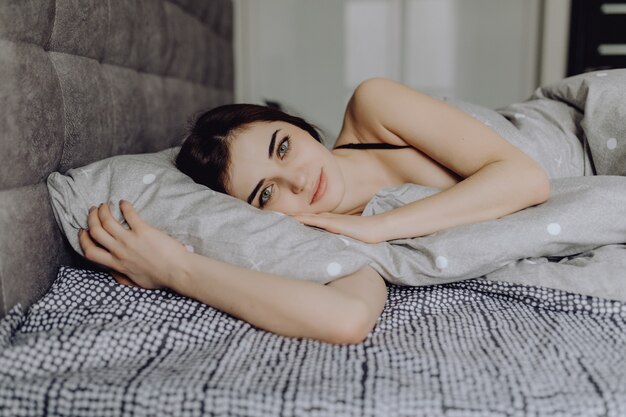 Hermosa chica en la cama Hermosas mujeres jóvenes tumbado en el sofá y sonriendo a la cámara