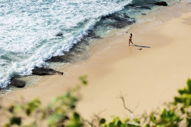 Hermosa chica camina por la playa salvaje. increíble vista superior.