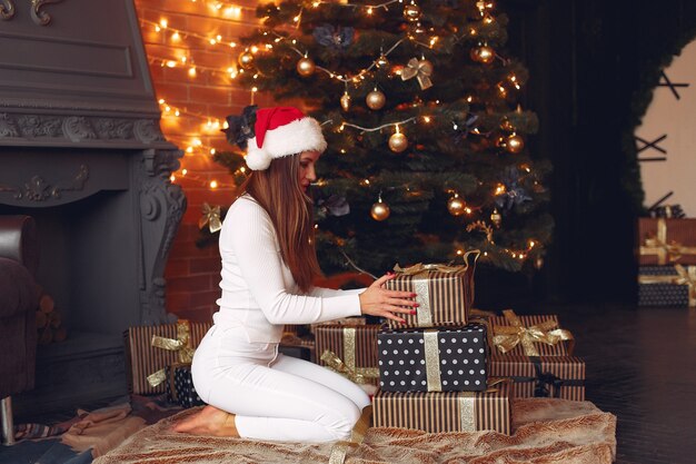 Hermosa chica en casa cerca del árbol de navidad