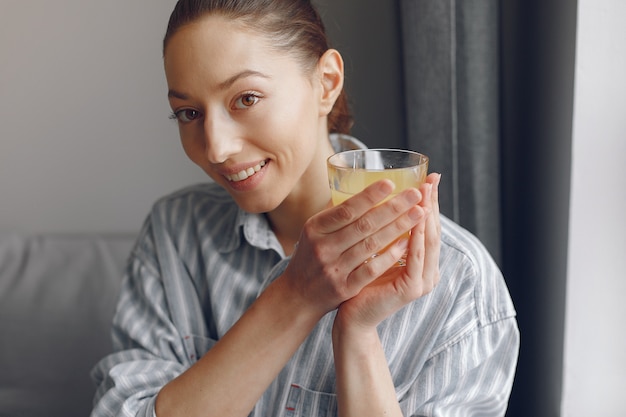 Hermosa chica en casa con jugo de naranja