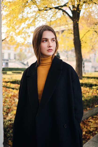 Hermosa chica casual cuidadosamente mirando hacia otro lado de pie sola en la calle de la ciudad de otoño