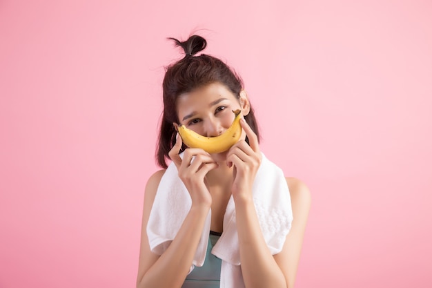 Hermosa chica comiendo bananas después de hacer ejercicio para controlar el peso.