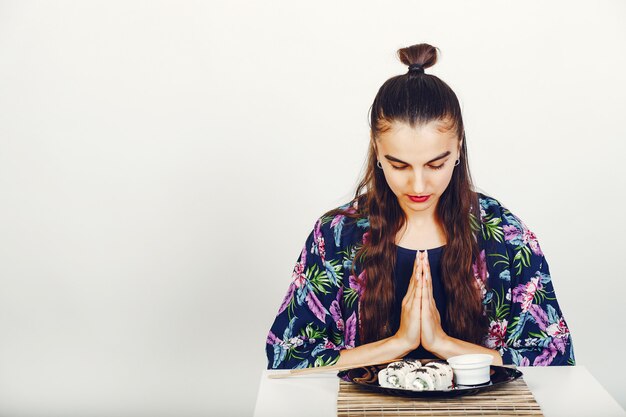 Hermosa chica comiendo un sushi en un estudio