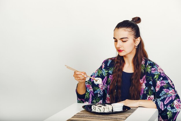 Hermosa chica comiendo un sushi en un estudio