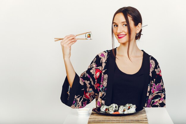 Hermosa chica comiendo un sushi en un estudio