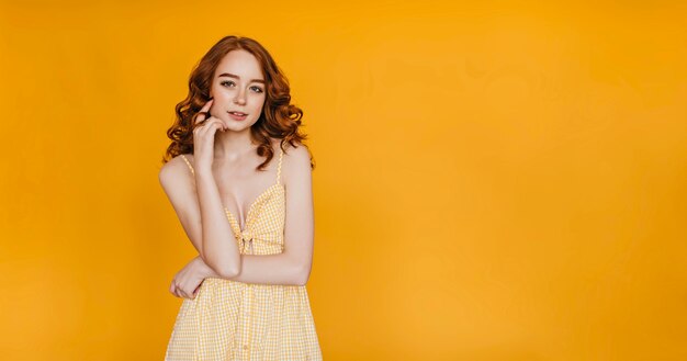 Hermosa chica delgada con cabello rojo posando. Retrato de mujer linda caucásica expresando interés.