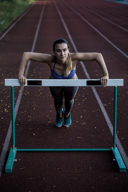 Hermosa chica deportiva calentando en el estadio, de cerca