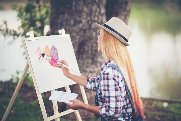 Hermosa chica dibuja una imagen en el parque