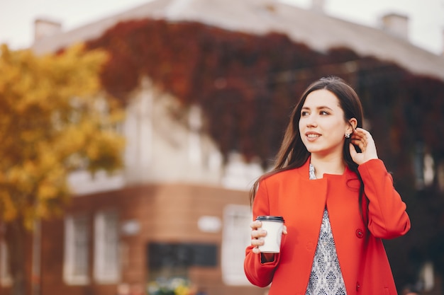 hermosa chica elegante caminando por la ciudad de otoño con teléfono