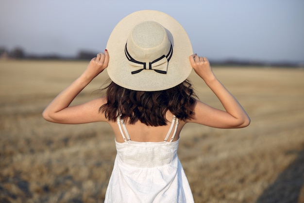 Hermosa chica elegante en un campo de trigo de otoño