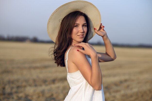 Hermosa chica elegante en un campo de trigo de otoño