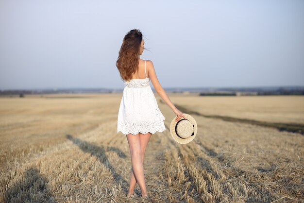 Hermosa chica elegante en un campo de trigo de otoño