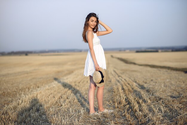 Hermosa chica elegante en un campo de trigo de otoño