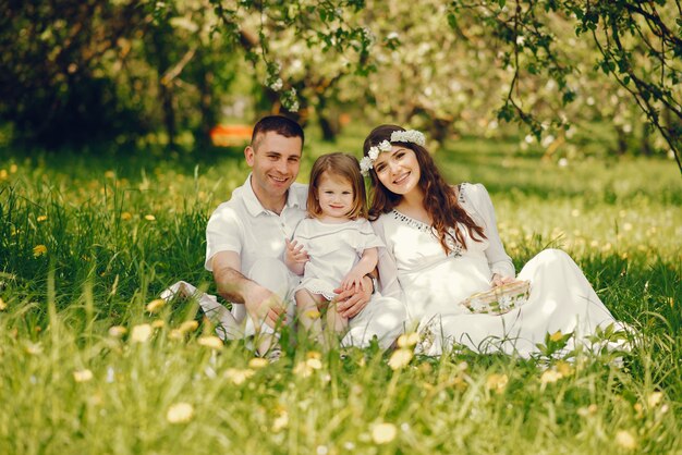 hermosa chica embarazada en un vestido blanco largo con su novio y su pequeña hija