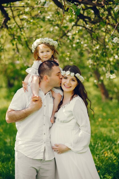 hermosa chica embarazada en un vestido blanco largo con su novio y su pequeña hija