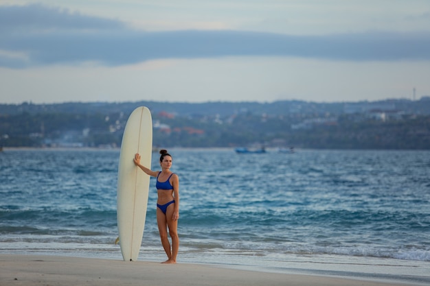Foto gratuita hermosa chica se encuentra en la playa con una tabla de surf.