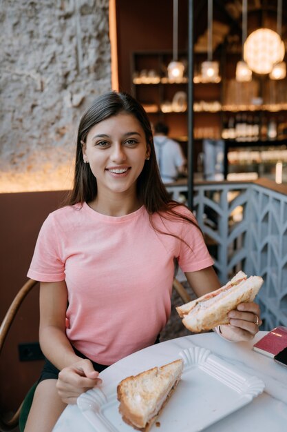 Hermosa chica está comiendo sandwich