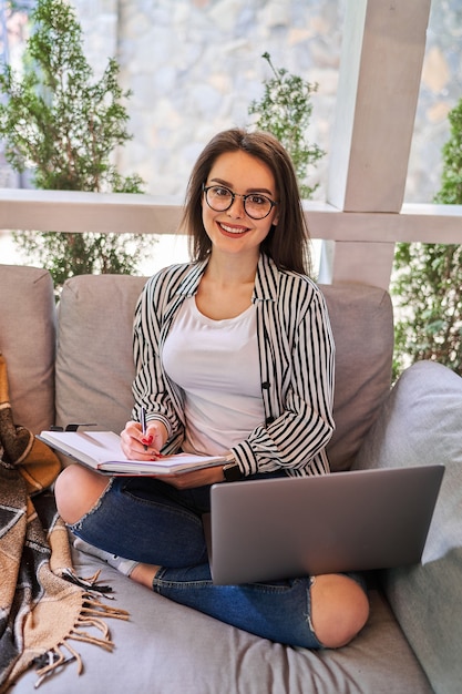 Hermosa chica estudiante aprendiendo en casa en el sofá.