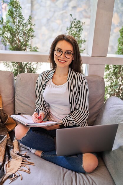 Hermosa chica estudiante aprendiendo en casa en el sofá.