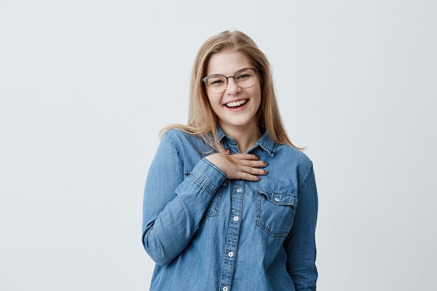 Hermosa chica europea mira con deleite, muestra dientes blancos perfectos, expresa positividad, se alegra de compartir el éxito con personas cercanas, aislado. Concepto de felicidad