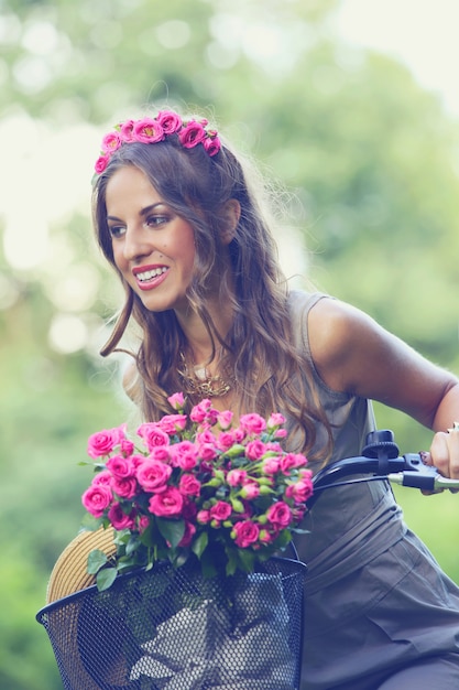 Hermosa chica con flores en bicicleta