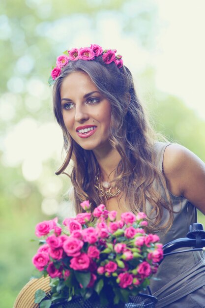 Hermosa chica con flores en bicicleta