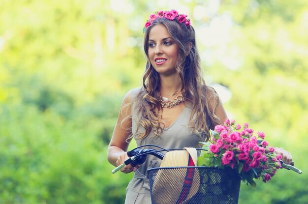 Hermosa chica con flores en bicicleta