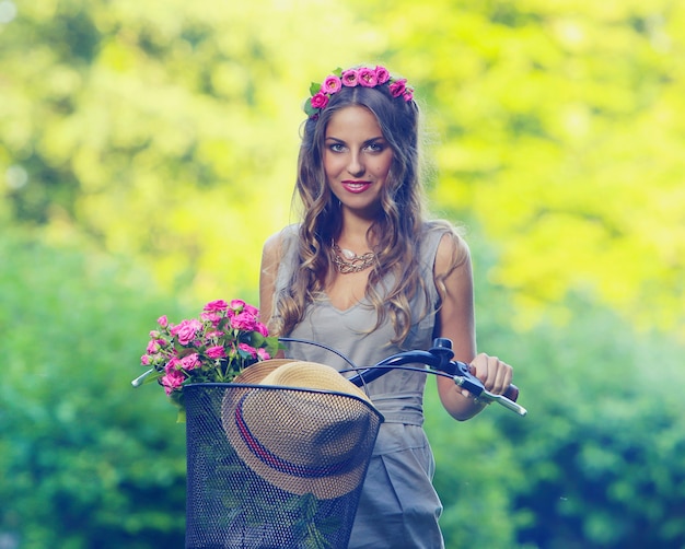 Hermosa chica con flores en bicicleta