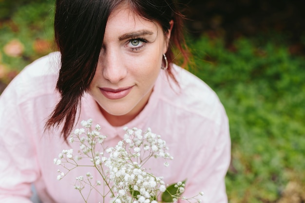 Hermosa chica con flores blancas en el parque