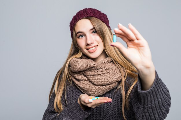 Hermosa chica con gripe o resfriado tiene una gran cantidad de medicamentos para tomar para estar saludable en gris