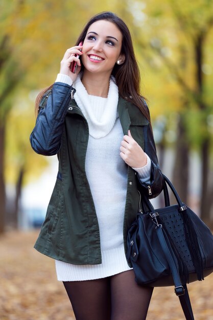 Hermosa chica hablando por teléfono en otoño.