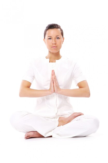 Hermosa chica haciendo ejercicios de yoga en blanco