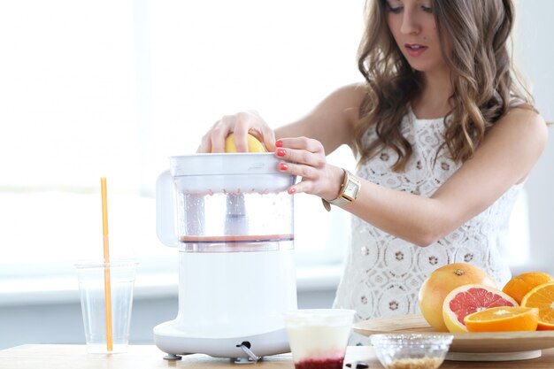 Hermosa chica haciendo jugo de naranja