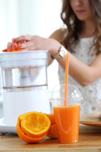 Hermosa chica haciendo jugo de naranja