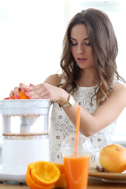 Hermosa chica haciendo jugo de naranja