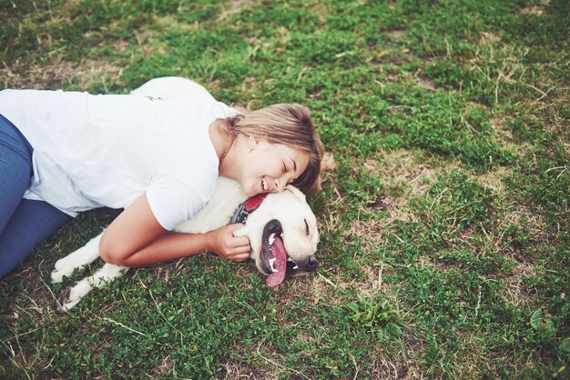 hermosa chica con un hermoso perro en un parque sobre la hierba verde.