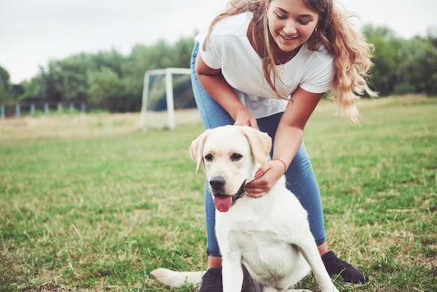 hermosa chica con un hermoso perro en un parque sobre la hierba verde.