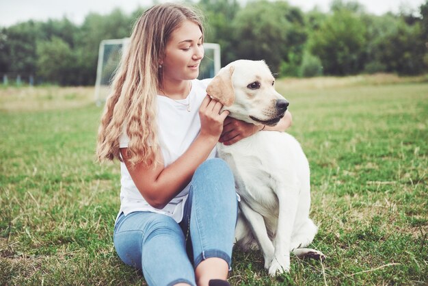 hermosa chica con un hermoso perro en un parque sobre la hierba verde.