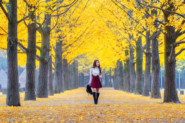 Hermosa chica con hojas amarillas en la isla de Nami, Corea.