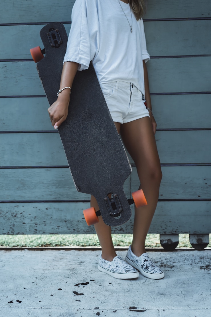 Foto gratuito hermosa chica joven sexy en pantalones cortos con longboard en tiempo soleado