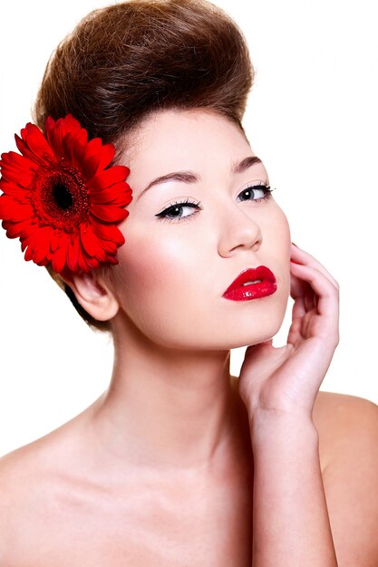 Hermosa chica con labios rojos y uñas con una flor en el pelo