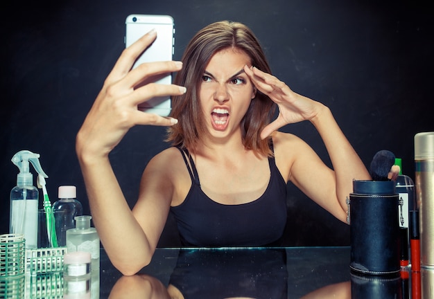 Hermosa chica mirando el teléfono móvil y haciendo foto selfie